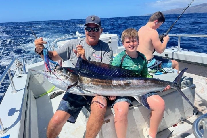 Doug Brochu holding a fish on a boat in the water